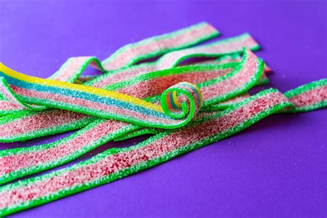 Rainbow Stripes Of Sour Jelly Candies In Sugar Sprinkles On A Purple