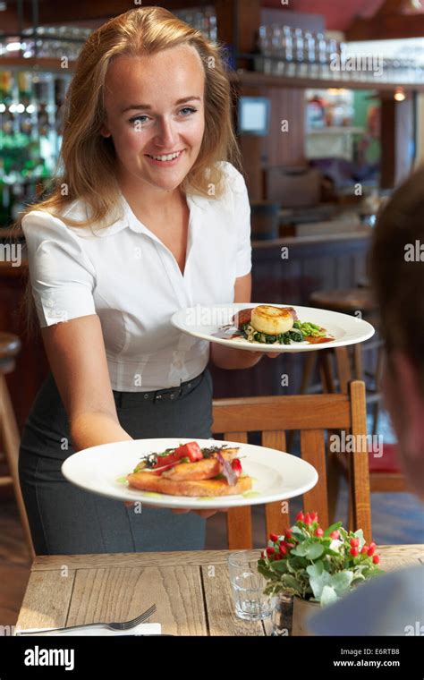 Waitress Serving Customer Sitting At Table In Restaurant Stock Photo