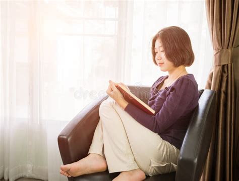 Young Asian Woman Short Hair Read A Book In Living Room Stock Image