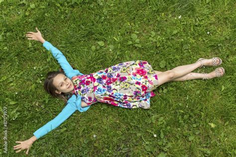 Cute Little Girl Lying On The Grass Arms Outstretched Top View