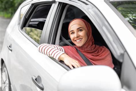 Cheerful Pretty Millennial Middle Eastern Female In Hijab Ride In Car With Driver Looks Out