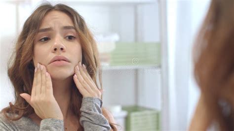 Upset Woman Looking Face And Touching Skin Front Bathroom Mirror In