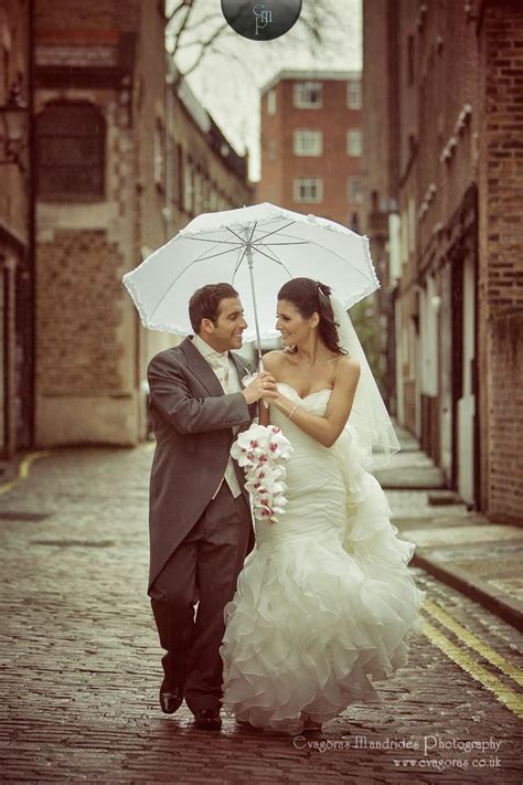 Check spelling or type a new query. Bride and groom walking in the rain on a cobbled street with a white umbrella on their wedding ...