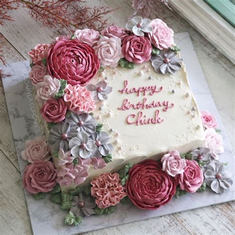A Birthday Cake Decorated With Pink And Grey Flowers