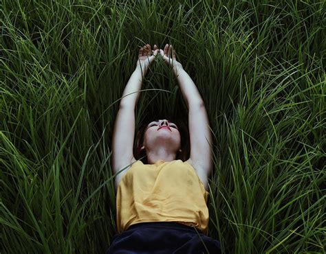 Young Woman Lying Down On A Green Grass Photograph By Cavan Images