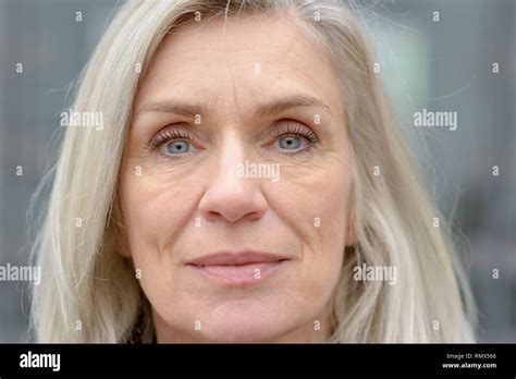 close up cropped portrait of an attractive blue eyed mature woman with long blond hair looking