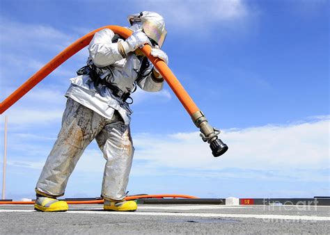 Firefighter Carries A Charged Hose Photograph By Stocktrek Images