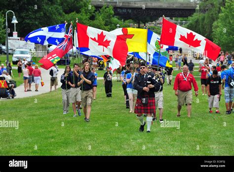 A Bagpiper Leads A Precession Of Canadian Flags At A Canada Day