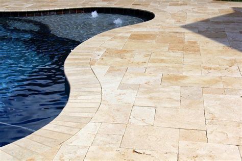 A Swimming Pool With A Stone Patio And Paver Walkway