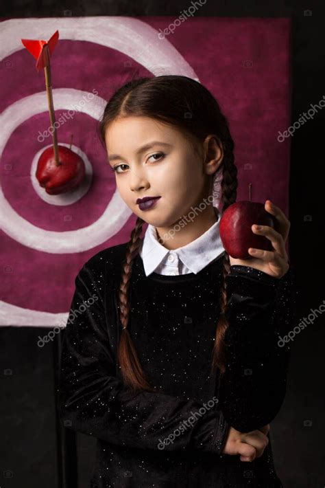 una chica sombría con coletas cerca de un objetivo con una flecha y una manzana en un estilo