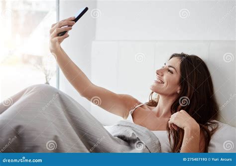 Starting The Day With A Selfie A Beautiful Young Woman Talking Selfies While Lying In Bed
