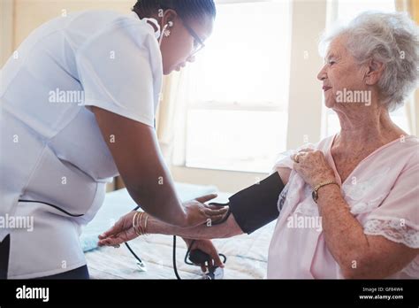 Home Nurse Doing Blood Pressure Measurement Of A Senior Patient Doctor