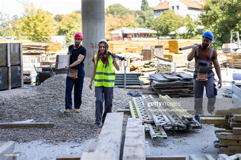 Young Multicultural Construction Workers Is Carrying Wooden Planks At A