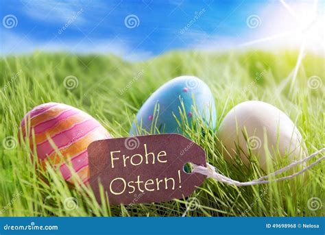 Three Colorful Easter Eggs On Sunny Green Grass With Label With German