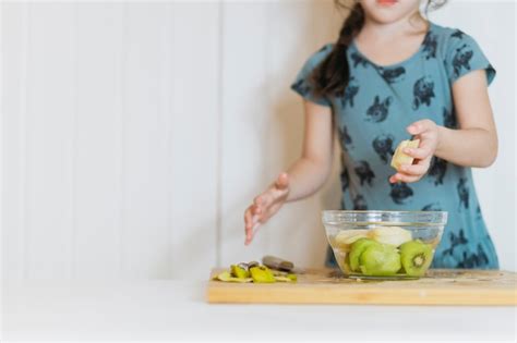 chica poniendo frutas en un tazón foto gratis