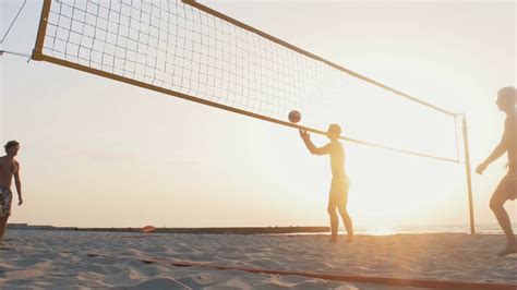 Group Of People Playing Beach Volleyball During Sunrise Or Sunset Stock