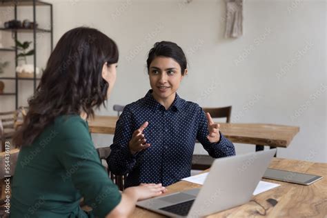 Positive Pretty Indian Mentor Woman Training Intern New Employee Talking To Coworker At Office