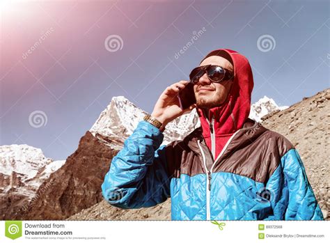 Young Man Using Cell Phone In Remote High Altitude Mountains Sunny