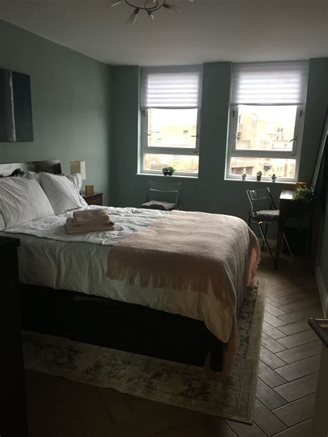 A Large Bed In A Bedroom Next To Two Windows