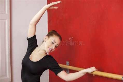Ballet Dancer Stretching Hand At Barre In Studio Stock Image Image Of