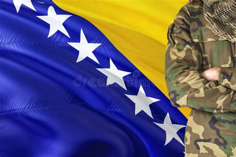 Crossed Arms Bosnian Soldier With National Waving Flag On Background