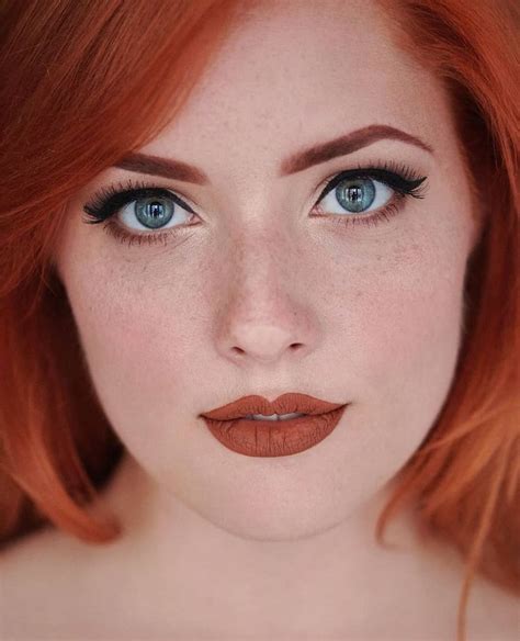 A Woman With Red Hair And Blue Eyes Wearing Orange Lipstick Looks At