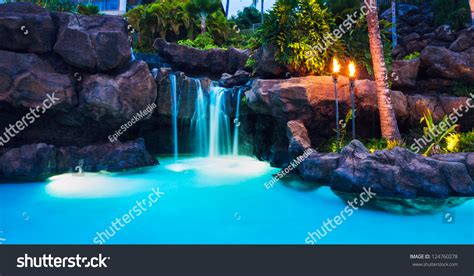 Tropical Resort Pool And Waterfall At Sunset In Hawaii Stock Photo