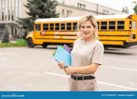 Portrait Of Cheerful Teacher Standing Near The School Bus Stock Image