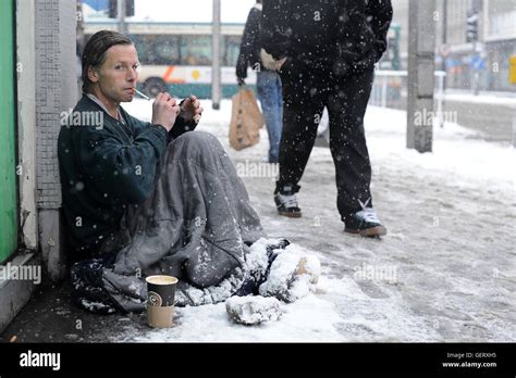 A Homeless Man Sits In The Street In Cardiff City Centre During Heavy