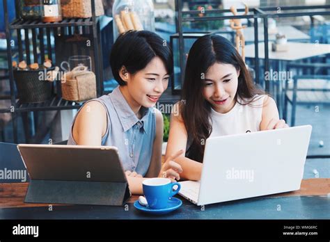 Women Using Computer Devices On Table In Cafe Stock Photo Alamy