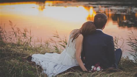2560x1440 Married Couple Sitting At Lake Watching Sunset 1440p