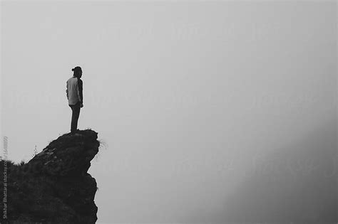Black And White Image Of A Man Standing At The Edge Of The Cliff