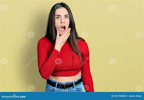 Young Brunette Teenager Wearing Red Turtleneck Sweater Looking Fascinated With Disbelief