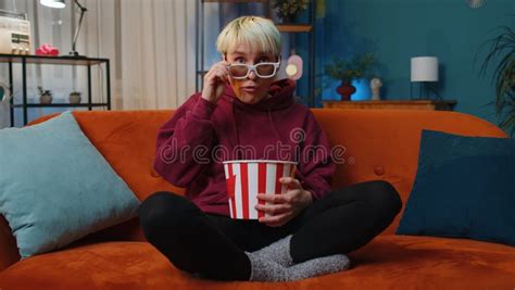 Woman Sitting On Couch Eating Popcorn And Watching Interesting Tv