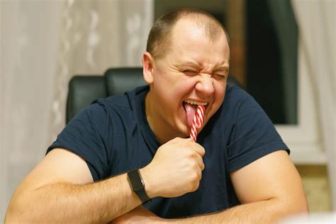 premium photo man licking a red and white christmas candy cane and making a disgusted face