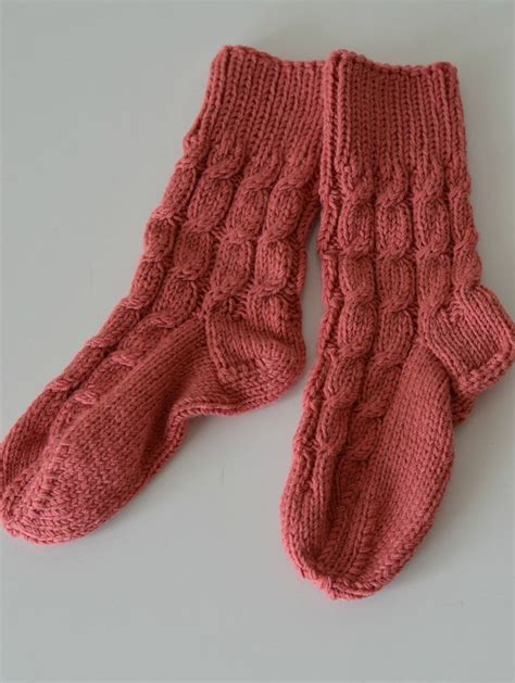 A Pair Of Pink Knitted Mittens Sitting On Top Of A White Countertop
