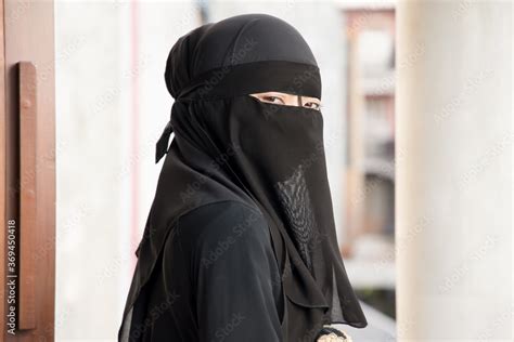 portrait of arabian woman looking at you while covering her face with niqab veil traditional