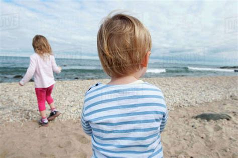 Preteen Girl Sitting On Beach With Barefeet Hugging Knees Stock Photo Dissolve