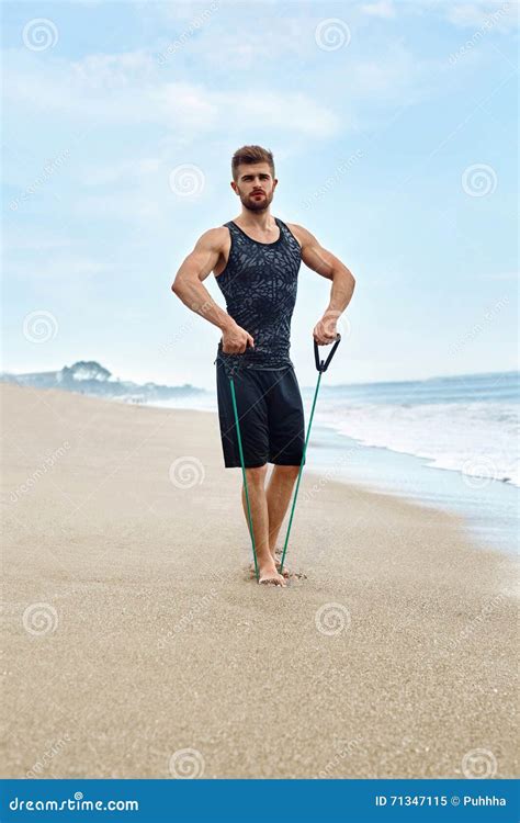 Fitness Man Exercising At Beach Doing Expander Exercise Outdoor Stock