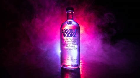 Download Majestic Absolut Vodka Bottle Amidst Purple Smoke Wallpaper