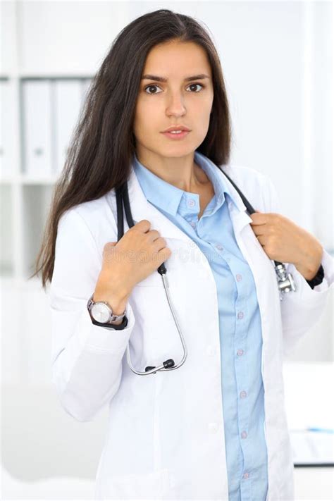 Young Brunette Female Doctor Standing And Smiling At Hospital Stock