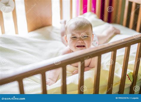 Close Up Portrait Of A Crying Cute Baby In The Crib At Home Stock Photo