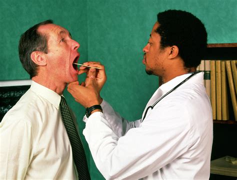 Gp Doctor Examining A Mans Throat Photograph By Cc Studioscience