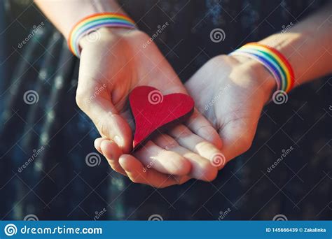 Female Hands With Lgbt Colorful Rainbow Ribbon Wristbands Holding Red