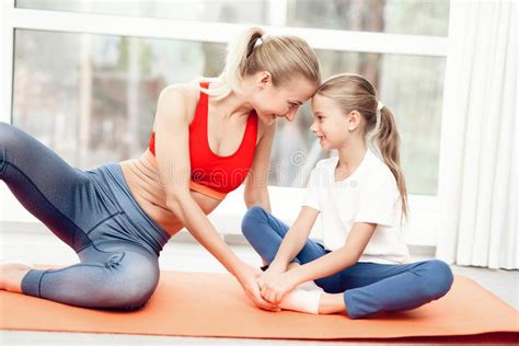 mother and daughter are engaged in yoga in sportswear they are in a bright room with panoramic