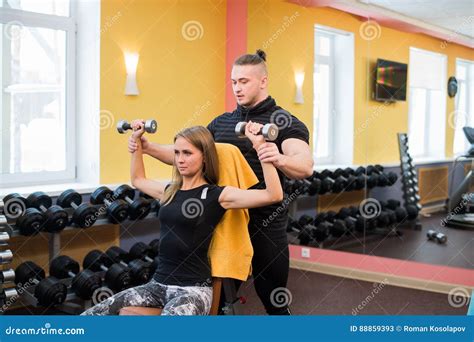 Woman With Her Personal Fitness Trainer In The Gym Exercising Power