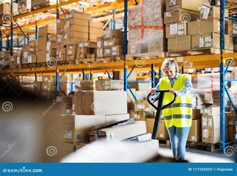 A Senior Woman Warehouse Worker Pulling A Pallet Truck With Boxes Stock Image Image Of Handle
