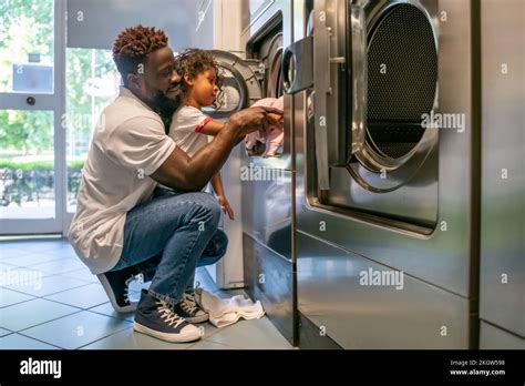 Father and daughter loading laundry into a washer Stock Photo - Alamy