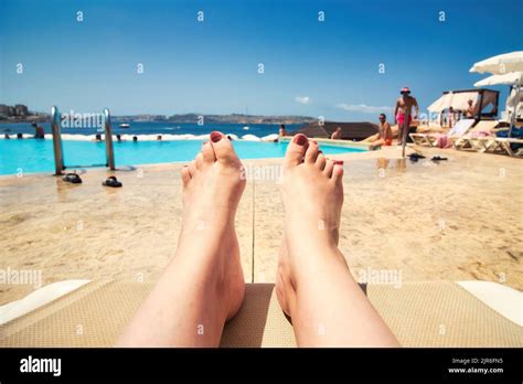 first person point of view from a woman lying relaxed on a poolside sun lounger looking at the