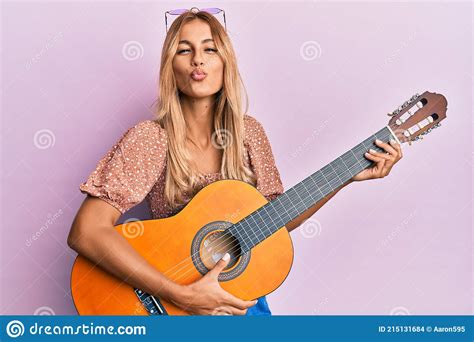 Beautiful Blonde Young Woman Playing Classical Guitar Looking At The